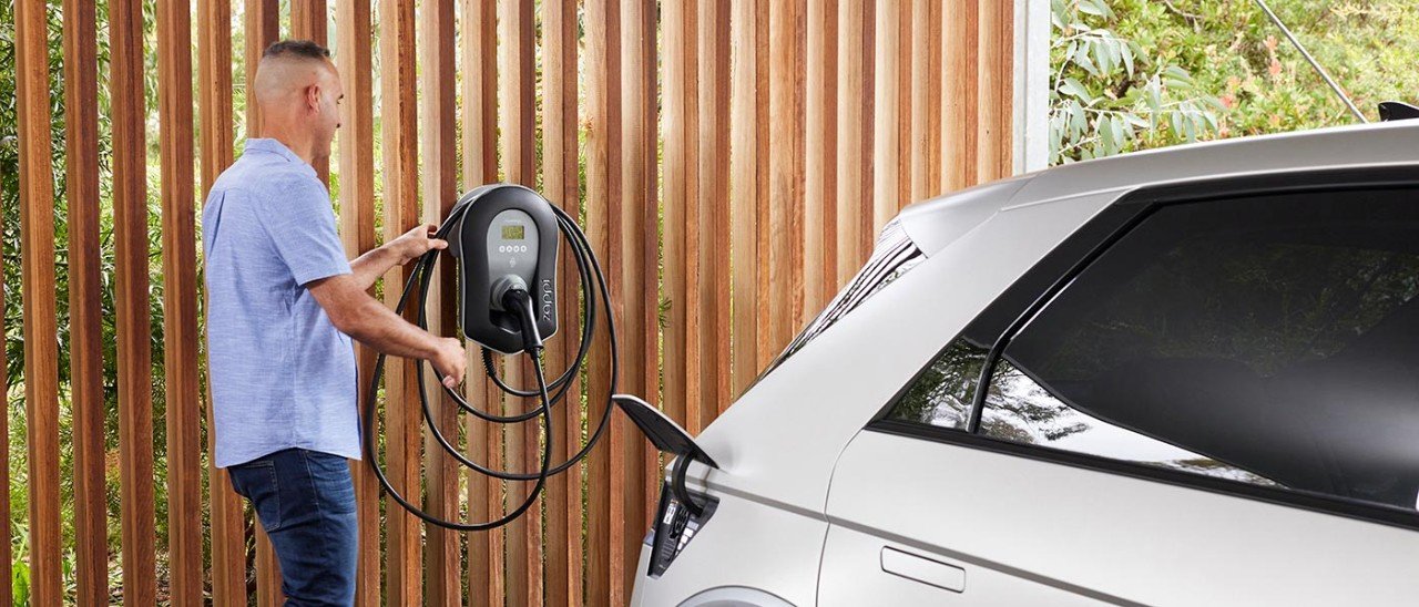 Homeowner using residential EV charger installed at modern home in South Florida
